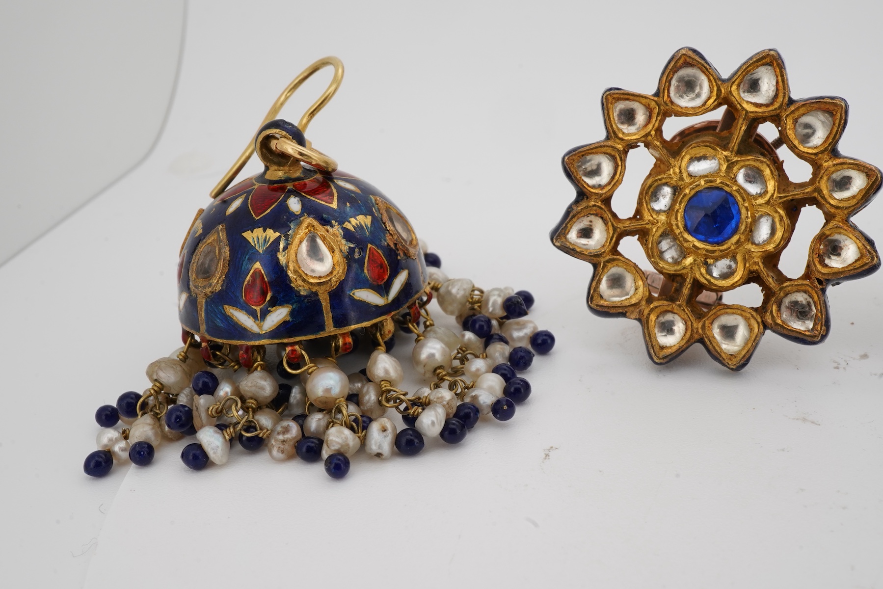 Two pairs of Indian enamelled earrings, comprising: one of chandelier design, set with rock crystals and applied with blue, white and red enamel, suspending a fringe of cultured pearls and blue and red pastes, length 5.1